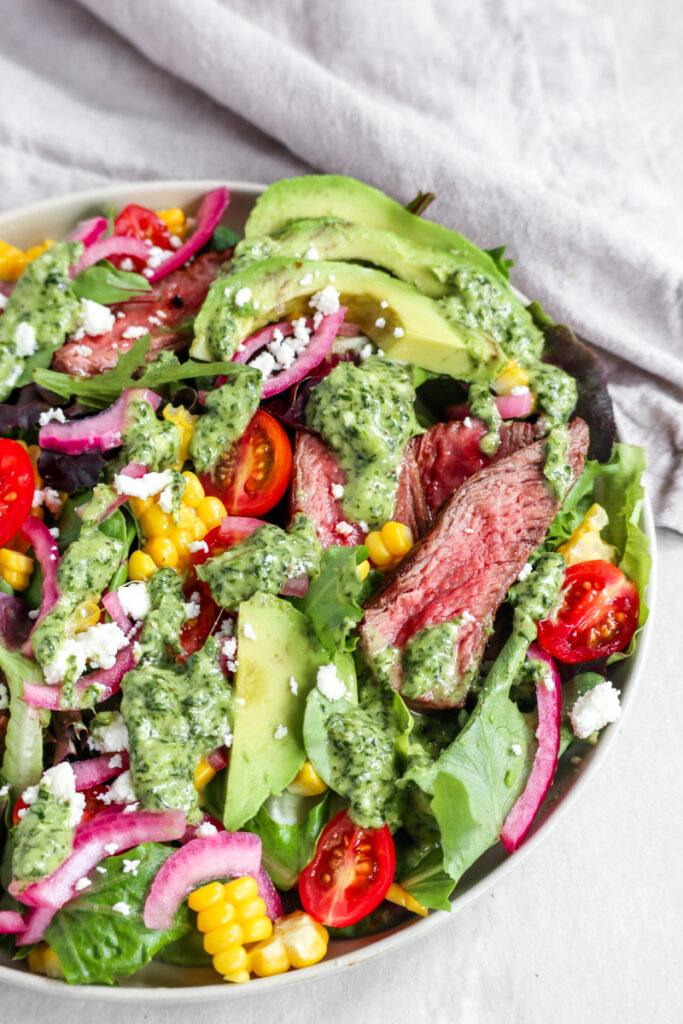 a steak salad with cilantro lime vinaigrette on a white plate